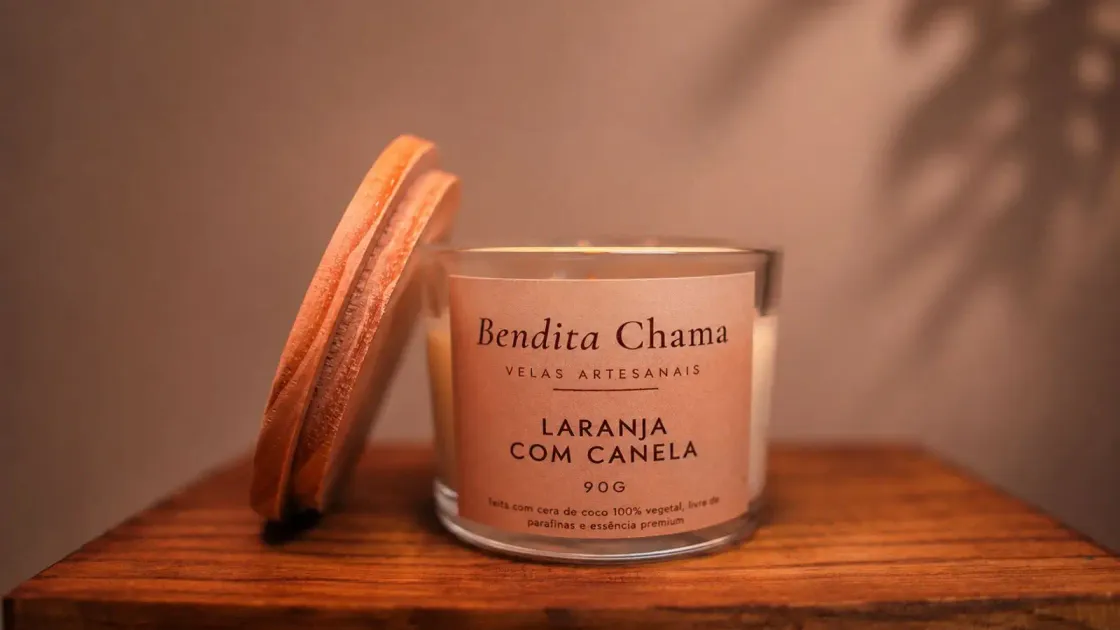Vela Bendita Chama Laranja com Canela de 90 g, acesa sobre uma mesa de madeira.